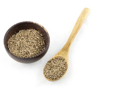 dried cumin in a wooden spoon and bowl wood on white backgroundの写真素材