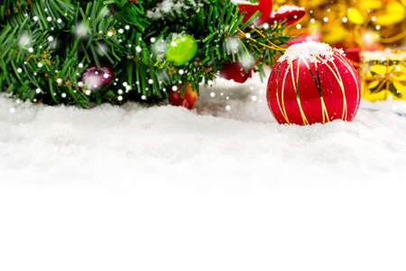 Christmas background with a red ornament, golden gift box in snowの写真素材