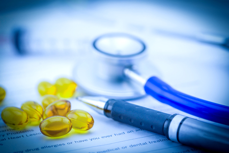 Medical questionnaire, stethoscope, pen and Fish oil capsules with document in blue toneの写真素材