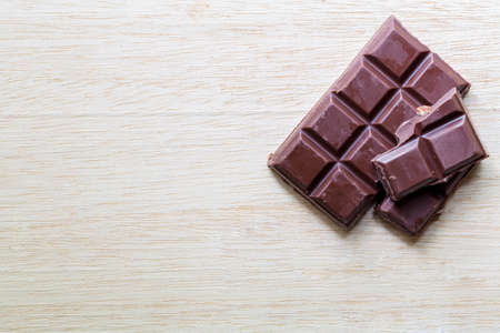 split bar of dark chocolate on wooden tableの写真素材
