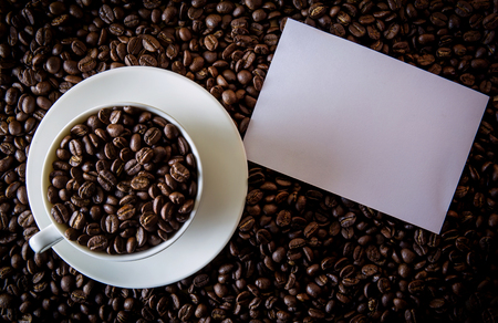 Cup of coffee on beans and note paper blankの写真素材