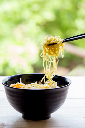 Chinese egg noodles with chopsticks on wood tableの写真素材