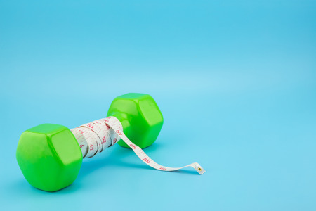 dumbell and measure tape isolated on blue background, healthcare conceptの写真素材