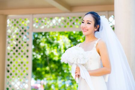 beautiful young woman on wedding day in white dress in the garden. Female portrait in the park.の写真素材
