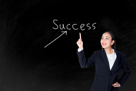 Happy young business woman pointing to success text with blackboard backgroundの写真素材