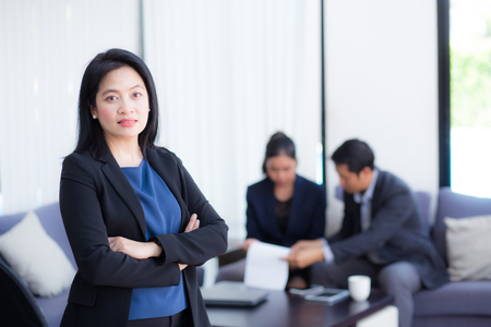 Beautiful woman standing with arms folded with colleagues in team on background.の写真素材