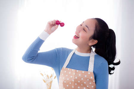 young woman eats fresh grapes in kitchen at home.の写真素材