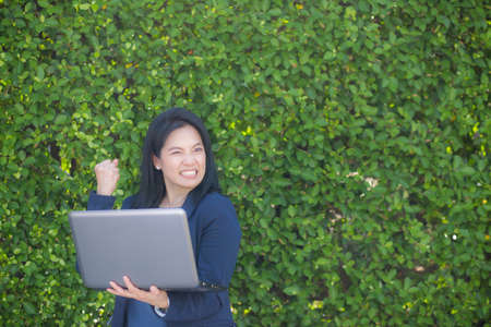 businesswoman holding computer notebook and showing making the glad gesture.の写真素材