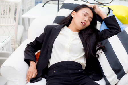 Tired executive sleeping lying on a sofa in the living room at home after workの写真素材