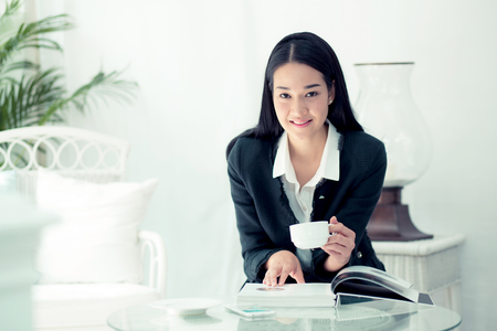Young businesswoman sitting at table in coffee shop and reading book.の写真素材