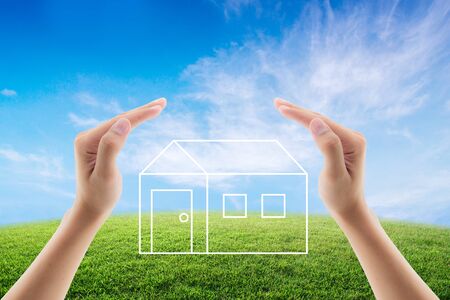 House sketch hand draw over blue sky with green field with hand.の写真素材