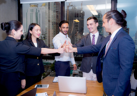Portrait of happy business partners looking at camera with smiles and geture of teamwork.