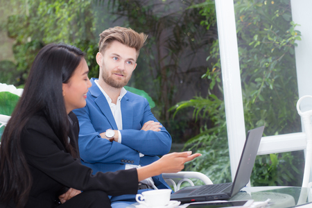 technology and office concept - two business man and woman with laptop - tablet pc computer and papers having discussion in office.の写真素材