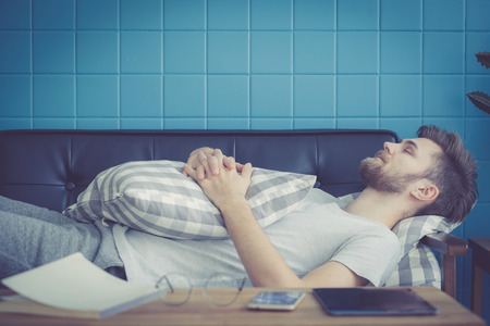 businessman with sleeping on sofa with book on table at home.
