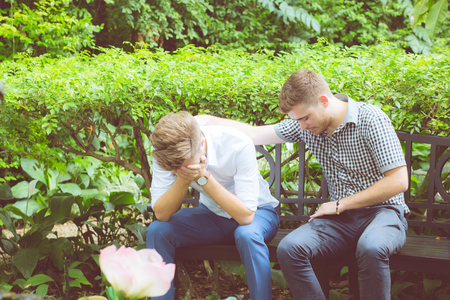 American businessmen consoling friend. Frustrated young man being consoled by his friend in garden.の写真素材