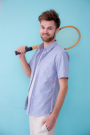 Portrait of american man standing sports with tennis racket ion pink background.の写真素材