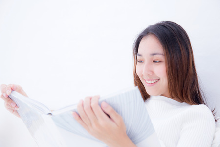 Asian woman reading a book and smiling in bedroom. lifestyle concept.の写真素材