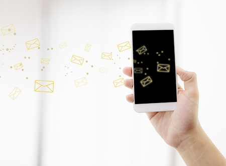 Hand holding man check and sending message with email in a phone on white background, communication concept.の写真素材