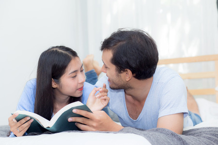 Couple reading a book together in bedroom on the morning with happiness.の写真素材