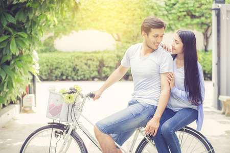 Asian young couple riding on bicycle with happy and fun at the park with romantic love, activity for leisure, relationship concept.の写真素材