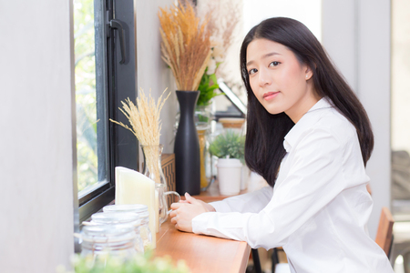 Beautiful of portrait asian young woman working online sitting at coffee shop, professional female freelancer relax and leisure, business concept.の写真素材