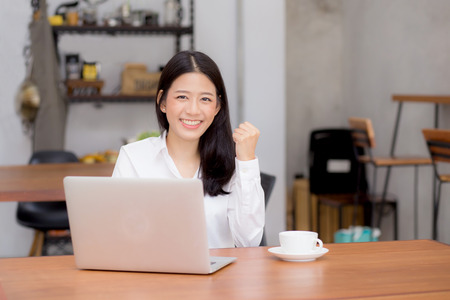 Beautiful asian young businesswoman excited and glad of success with laptop, girl using working computer coffee shop on desk, career freelance business concept.の写真素材