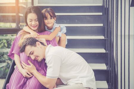 man is listen pregnant of wife, asian handsome father take care mother and kid with couple and expect maternity have a happy, love of family concept.の写真素材