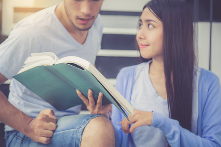 Closeup couple asian handsome man and beautiful woman reading book and glad at home, boyfriend and girlfriend with activities together for leisure, education success concept.の写真素材