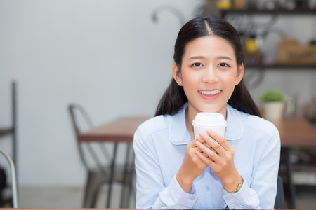 Beautiful young asian woman drinking coffee and smile in the morning at cafe, girl sitting in coffee shop for breakfast and leisure during free time.の写真素材