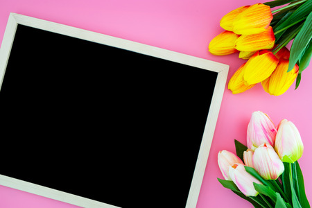 Beautiful of yellow tulip flower and chalkboard, blackboard with flat lay on the pink background, top view, copy space, mother day and holiday concept.の写真素材