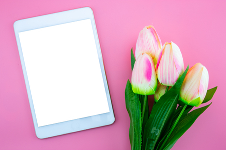 Beautiful of yellow tulip flower and tablet, with flat lay on the pink background, top view, copy spaceの写真素材