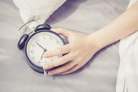closeup asian young woman turn off alarm clock in good morning, wake up for sleep with  girl holding...