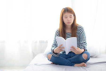 Beautiful of portrait young asian woman relax sitting reading book on bedroom at home, girl study literature, education and llifestyle concept.の写真素材