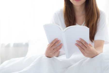 Beautiful of portrait young asian woman relax sitting reading book on bedroom at home, girl study literature, education and llifestyle concept.の写真素材