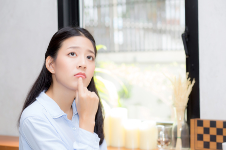 Portrait of beautiful young asian woman happiness and think sitting at cafe shop, businesswoman is a smile, freelance people concept.の写真素材