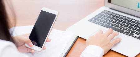 closeup banner website asian woman sending email contact. gesture of finger pressing send on mobile smart phone and laptop computer, technology communication concept.の写真素材