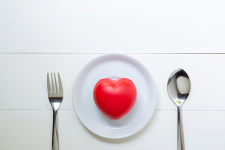 Red Heart with love and dish and spoon and fork on wooden background, 14 February Valentine day, on grunge white wood, celebration and holiday concept, top view.の写真素材