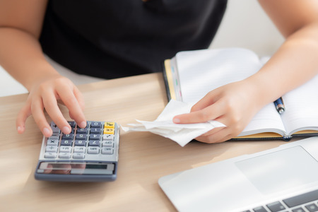 closeup hand woman calculating expenses household and writing notebook on desk, girl checking bill...