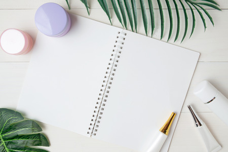 cosmetic and skin care product and notebook and leaves on table, beauty with treatment cream and moisturizing and notepad copy space on wooden desk, health and wellness concept, top view.の写真素材