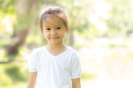 Portrait face of cute asian little girl and child happiness and fun in the park in the summer, smile and happy from asia kid and relax in the garden, lifestyle childhood concept.の写真素材