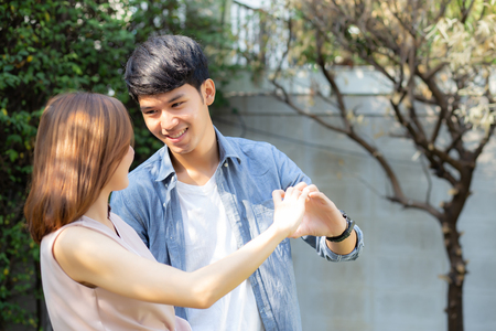 Beautiful happy young couple fun making gesture heart shape with hand outdoor together, man and woman with relation feeling love with symbol and sign in the garden, lover and romantic concept.の写真素材