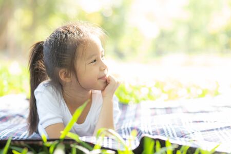 Portrait face of cute asian little girl and child happiness and fun in the park in the summer, smile and happy from asia kid and relax in the garden, lifestyle childhood concept.の写真素材