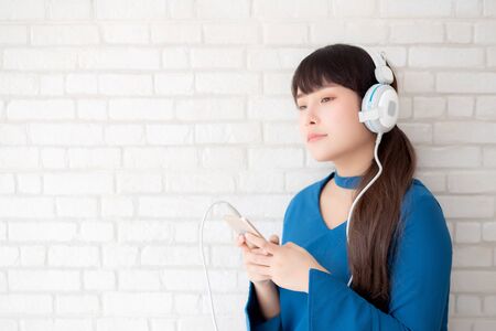Beautiful portrait asian young woman standing happy enjoy and fun listen music with headphone on...