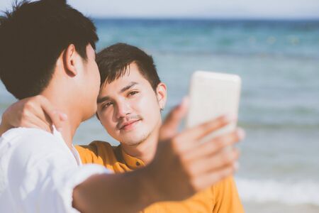 Portrait young couple smiling taking a selfie photo together with smart mobile phone at beachの写真素材
