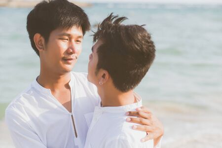 Homosexual portrait young asian couple standing hug together on beach in summer, asia gay going tourism for leisure and relax with romantic and happiness in vacation at sea, LGBT concept.の写真素材