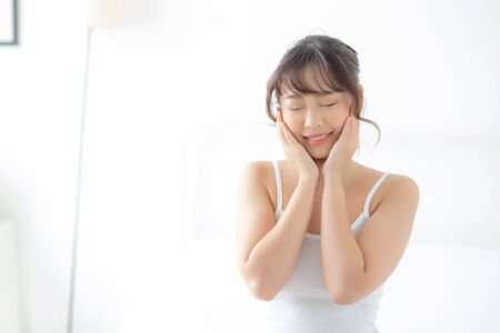 Portrait of beautiful young asian woman smile while wake up healthy and wellness with sunrise at morning in the bedroom, asia girl skin care with happy with fresh, lifestyle and relax concept.の写真素材