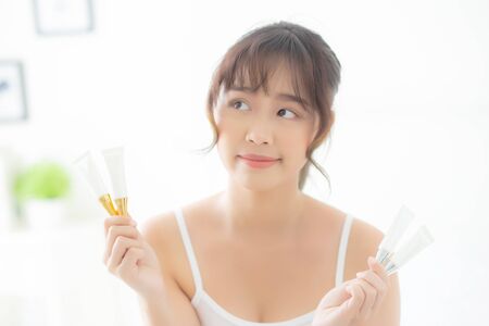 Beautiful portrait young asian woman holding and presenting cream or lotion product, beauty asia girl show cosmetic makeup and moisturizing for skin care, healthy care and wellness concept.の写真素材