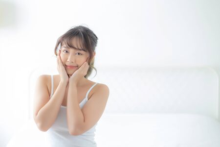 Portrait of beautiful young asian woman smile while wake up healthy and wellness with sunrise at morning in the bedroom, asia girl skin care with happy with fresh, lifestyle and relax concept.の写真素材