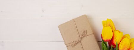 Beautiful tulip flower and gift box on wooden tableの写真素材