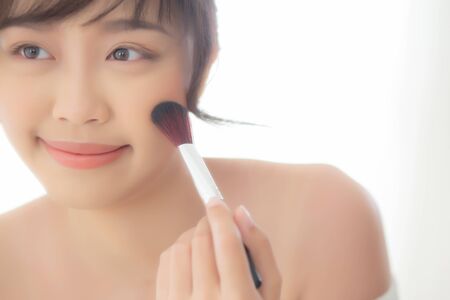 Beauty portrait young asian woman smile with face looking mirror applying makeup with brush on cheek